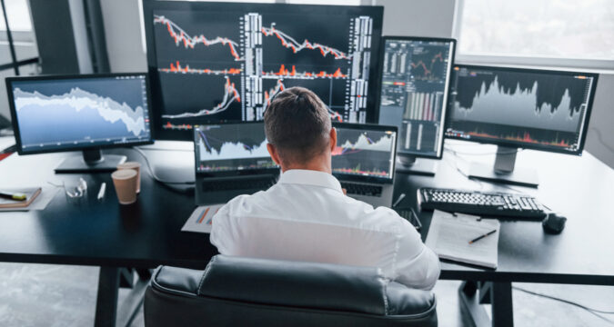 RearViewOfYoungMaleStockBrockerThatWorksIndoors | Cryptocoin Stock Exchange Emberprime.com Review, EmberPrime – Is Ember Prime Scam or a Good Broker?