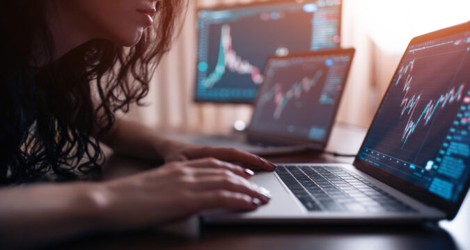 YoungFemaleTraderWithLaptopAndScreenLookingAtStock | Cryptocoin Stock Exchange Reseña de Worldwidechain.io (World Wide Chain) – Trading Confiable y Seguro en el que Puedes Confiar